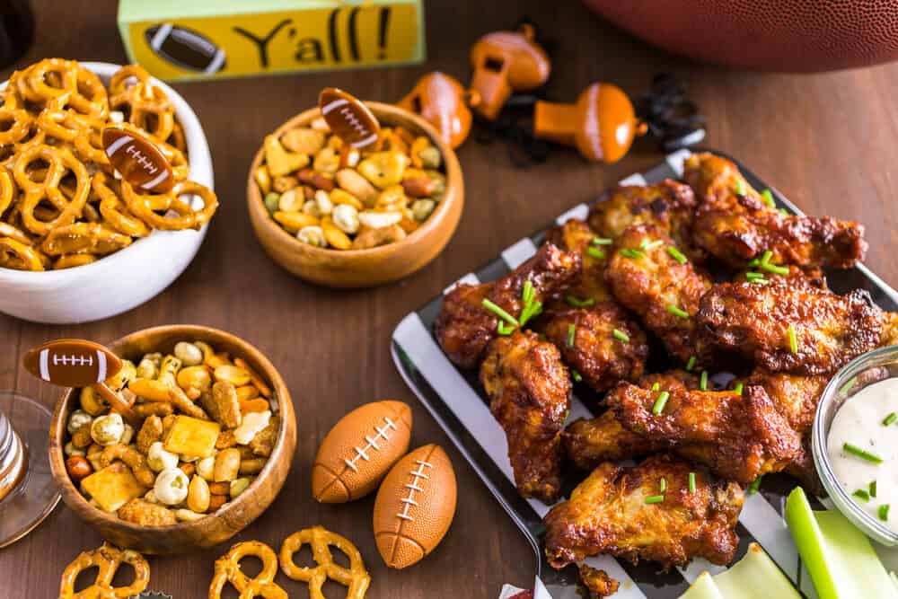 game day food ideas with a spread of appetizers like, buffalo wings, pretzels, and nuts.