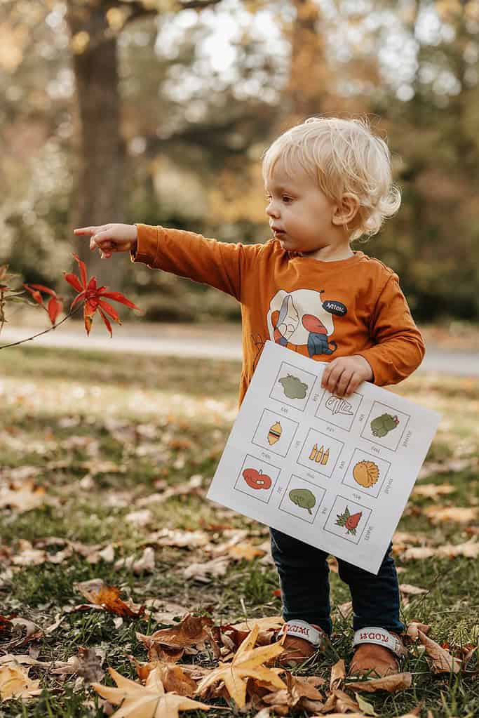 Toddler with a picture-based scavenger hunt sheet checking off items found during a walk.