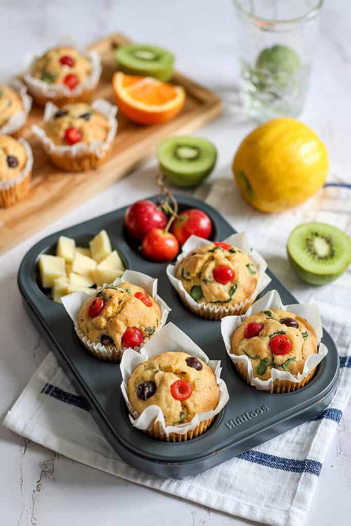 Colorful fruit muffins with cherries, blueberries, and mint, fresh fruit, healthy snack, baked goods.