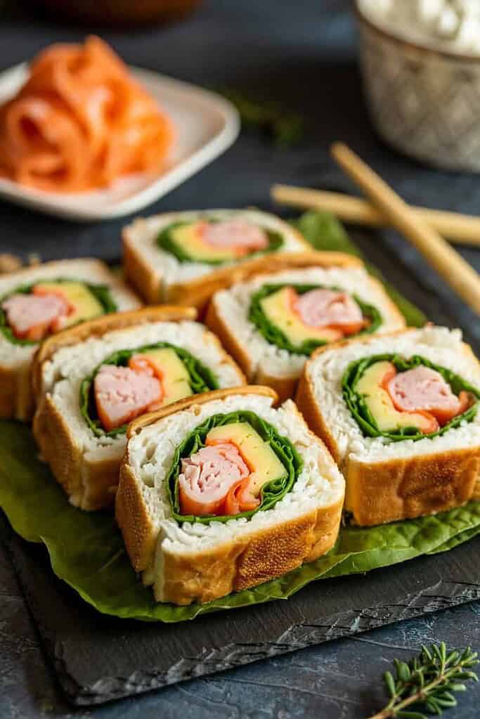 Sandwich sushi rolls cut into bite-sized pieces with colorful fillings inside.