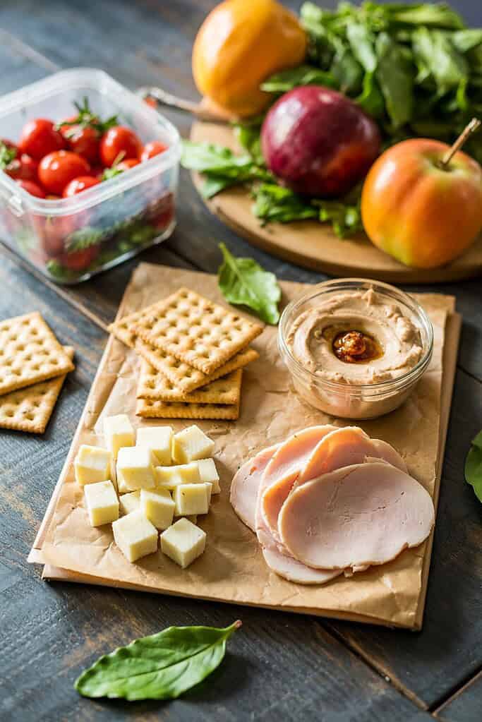 DIY lunchable with whole grain crackers, cheese cubes, and meat slices arranged in separate compartments.