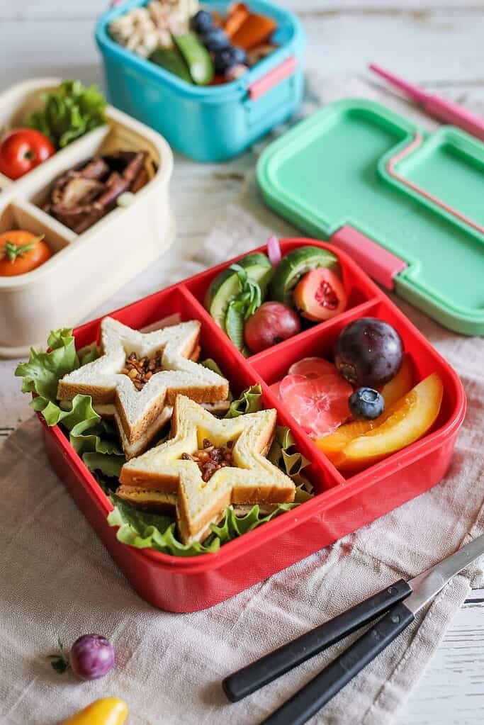 Colorful bento box with compartments filled with various healthy foods arranged neatly for a child's lunch.