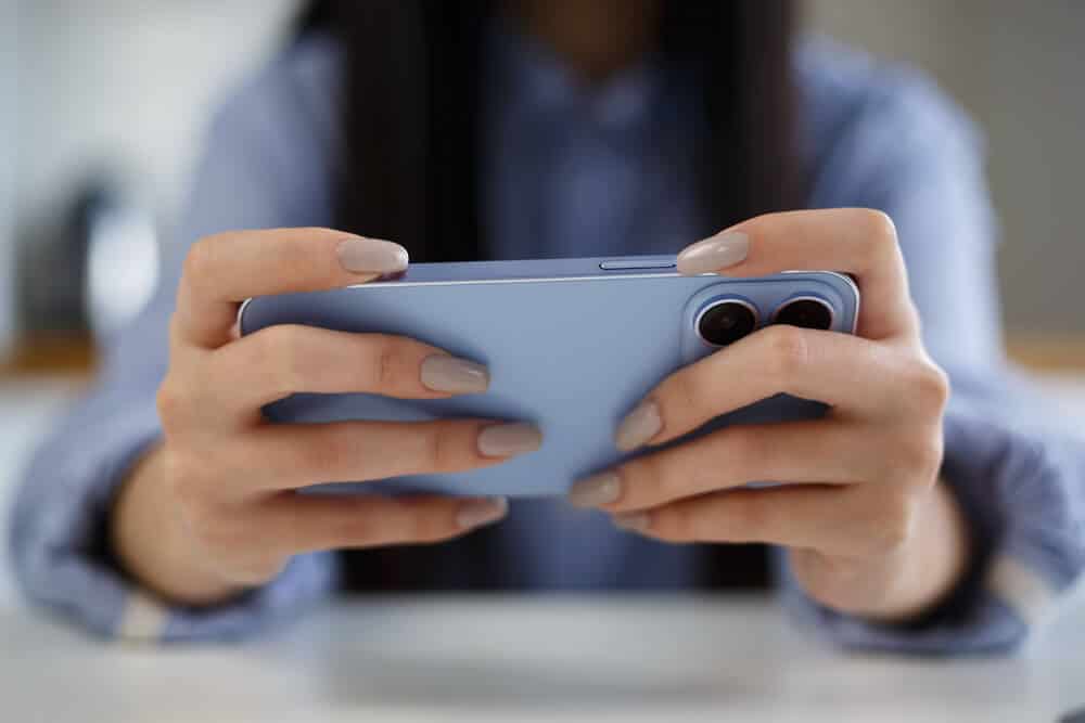 Mom holding blue phone, playing gaming apps.