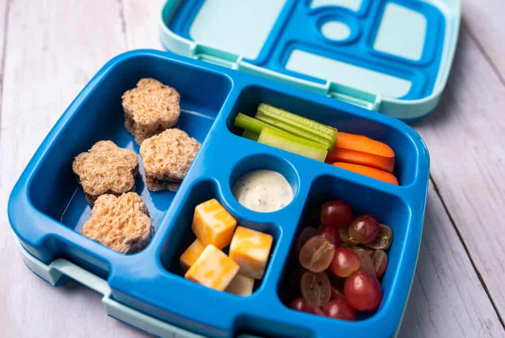 Kids bento box with sandwhich cut like stars. Cheese, fruit and veggies.